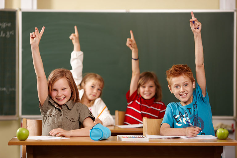 Bambini a scuola con le mani alzate